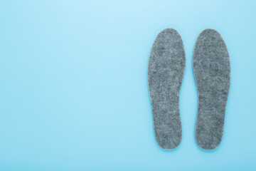 New gray soft natural felt insoles on light blue table background. Pastel color. Closeup. Flat lay. Empty place for text. Top down view.