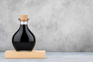 Elegant Balsamic Vinegar in Glass Bottle on Wooden Base Against Gray Background