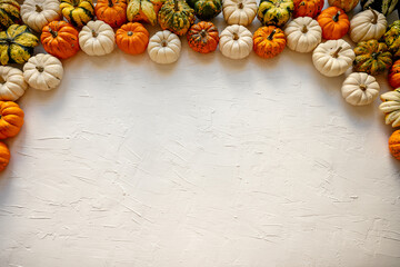Baby Boo Pumpkins and gourds arranging a decorative border on a white textured background, creating a festive autumn and Halloween flatlay with abundant copy space