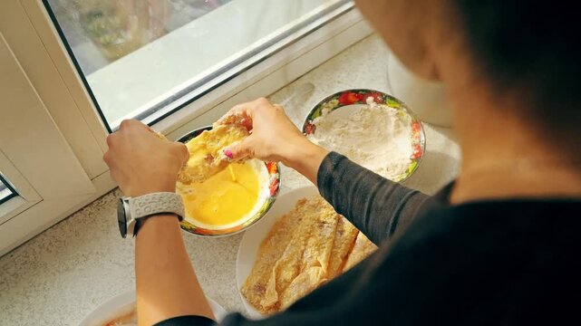 Woman preparing mintaj fish schnitzels with egg in slow motion kitchen dinner