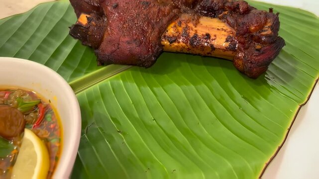 Roasted pork knuckle on a banana leaf plate