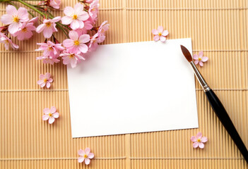 Blank paper with calligraphy brush and sakura flowers on wooden table background – Japanese style mockup template