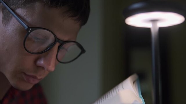Man reading book with desk lamp, concept of education, knowledge and self learning at home lifestyle