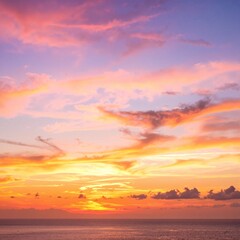 Fototapeta premium A breathtaking sunset casts vibrant hues of orange, pink, and purple across the sky, reflecting on the calm ocean waves, creating a serene atmosphere.