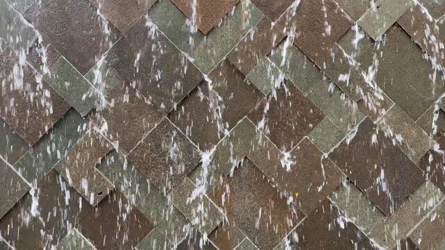 4k footage, close up cascading waterfall fountain on a slate stone. Seen here the water fountain droplets dropping, landscape garden design. Contemporary modern garden design waterfall.