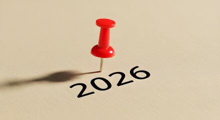 Red push pin stuck and marking the year "2026" on a calendar, planner brown paper surface 
