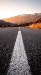 A paved road stretches into a distant mountain range bathed in the golden light of sunrise.