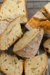 Close up view of sliced artisan sourdough bread pieces placed on a cooling rack in a bakery kitchen.