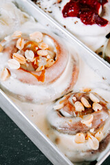 Warm cinnamon rolls topped with nuts and drizzle served in a metal tray