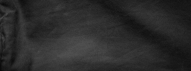 Slightly waving black rough cotton fabric texture with shabby details. Background.