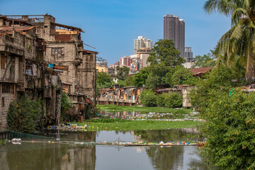 Slum Housing Along Polluted River with City Skyline in Manila
