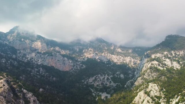 aerial footage showcasing the stunning natural beauty of Kelebekler Vadisi Butterfly Valley and the towering Babadag Mountain in Fethiye, Turkey. This serene landscape features lush green forests, dra
