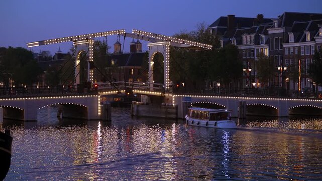Evening in Amsterdam, Cyclists and Pedestrians Crossing the Illuminated Magere Brug (Skinny Bridge) over Amstel River