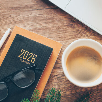 Stylish Desk Setup With 2026 Planner, Notebook, Pencil, Glasses and Cop of Coffee on Wooden Surface