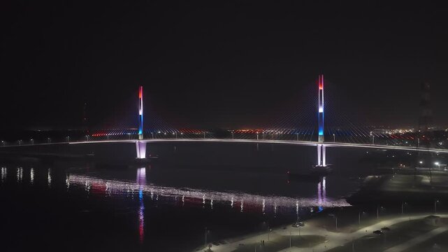 Backward drone flight over Heroes of Chaco Bridge reveals the Costanera avenue at night, Asuncion