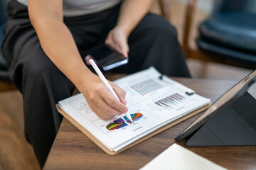 Person analyzing business data on report with stylus