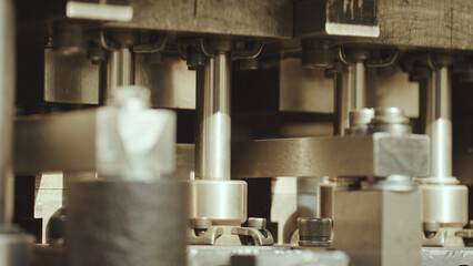 Mechanical components of industrial equipment working together, featuring metal parts, pistons, and fasteners, creating an intricate system within a factory production line