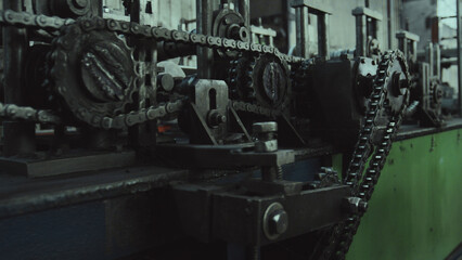 Fototapeta premium Interconnected steel chains and sprockets driving a production line, close up on rugged gears and mechanical linkages that showcase industrial power and precise manufacturing movement