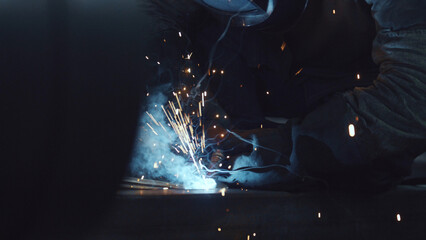Obraz premium Welder applying electric arc welding technique to join metal pieces in an industrial setting, generating bright sparks and smoke, showcasing a skilled trade in manufacturing