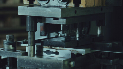 Industrial metal stamping machine operating with heavy steel dies, pressing and shaping production parts in a factory setting, illustrating precision engineering manufacturing processes