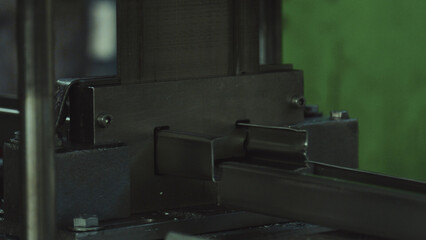 Industrial metal machine cutting and shaping a steel profile on a production line, highlighting precision fabrication, heavy industry equipment and automated manufacturing workflow