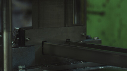 Metal profiles are handled by a specialized manufacturing machine in a factory setting, symbolizing industrial production, precision engineering, and automated fabrication processes