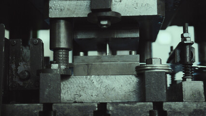 Industrial manufacturing machine performing a metal stamping process, shaping metal components with precision tooling, illustrating the intricacies of heavy industry and engineering production