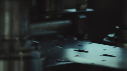 Industrial machine precisely punching and shaping a flat metal sheet with various slots and holes, showcasing modern manufacturing processes and mechanical engineering