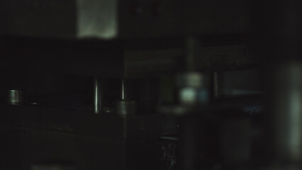 Industrial metal shafts and gears recede into shadow, revealing intricate, precise mechanical components in a factory settingdark, detailed, futuristic industrial engineering