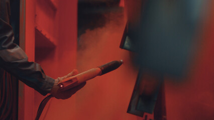 Worker applying powdered paint to a metal object using an electrostatic spray gun, creating a durable and even finish in a modern industrial production facility