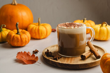 Pumpkin spice latte, coffee drink in glass cup with pumpkins, autumn hot drink