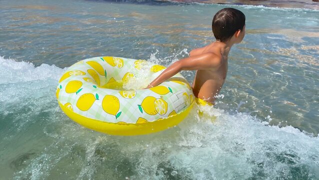 Boy having fun in the sea with an inflatable ring - Powered by Adobe