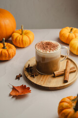 Pumpkin spice latte, coffee drink in glass cup with pumpkins, autumn hot drink