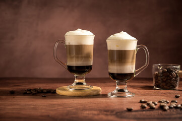 Layered coffee latte drinks. Hot coffee drinks in glass mugs, brown background