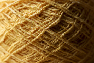 Warm macro closeup of yellow yarn ball shows intricate texture of string and fiber. cozy, inviting look for any creative craft or knit project
