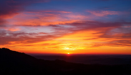 Obraz premium Vivid Sunset Over Horizon With Colorful Sky And Silhouetted Landscape