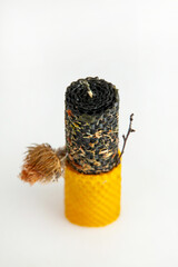 Natural hand-rolled beeswax candle with herbs on a light background