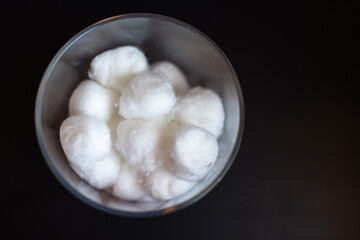 Fototapeta premium Close-up of fluffy clean white cotton balls in a clear jar against a dark background with copy space 