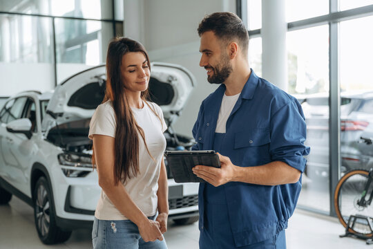 Giving the consultation. Woman customer is in the car repair service station with mechanic