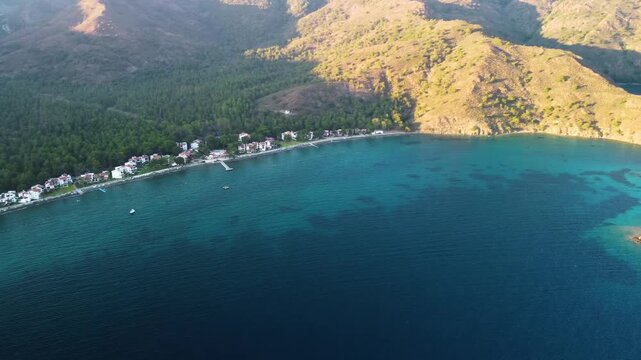 aerial perspective showcasing the stunning turquoise waters and rugged coastline of the Aegean Sea, leading towards the historic site of Knidos Ancient City in Turkey. The footage captures the serene 