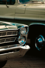 Fototapeta premium Front Chrome Details of Classic Green Car with Vintage Vehicle in Background