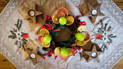 advent wreath decorated with candles, candy canes, dried oranges and pine cones