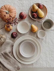 Overhead view of a dining table with pears and apples Top view of a dining table set with pears, apples, and a small pumpkin on a linen tablecloth. Cozy, rustic, and seasonal flat lay composition, ide