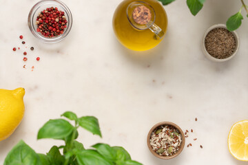 Marble light background with olive oil, basil, lemon, seeds and spices. Salad ingredients top view...