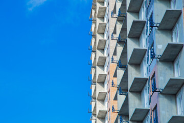 Close-up of an unfinished building with concrete boards for a balcony on the side against the blue sky. The concept of construction, finishing works, construction site, residential multi-storey