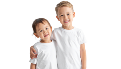 Two cheerful children in matching white t-shirts, standing closely together, smiling warmly at the camera.