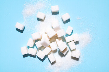 Scattered sugar cubes. White sugar cubes on blue background top view flat lay. Abstract pattern of food. Concept of sweets consumption and addiction, global issue of health 