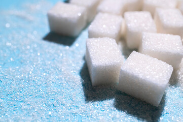 Scattered cubes of white refined sugar close-up. Food background, sweetness, cooking ingredient. Sugar addiction concept, unhealthy eating