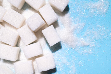 Scattered cubes of white refined sugar close-up. Food background, sweetness, cooking ingredient. Sugar addiction concept, unhealthy eating
