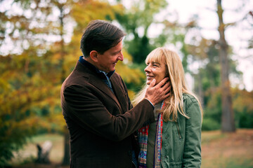 Fototapeta premium Mature couple having a tender moment in an outdoor park during autumn